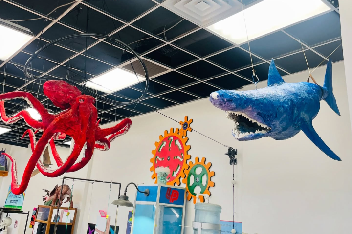 Hanging red octopus and blue shark sculptures in a room with colorful wall art.