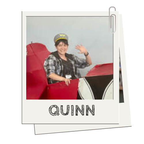 Person in a red car cutout with a hat, waving, named 'QUINN' in a Polaroid-style photo.