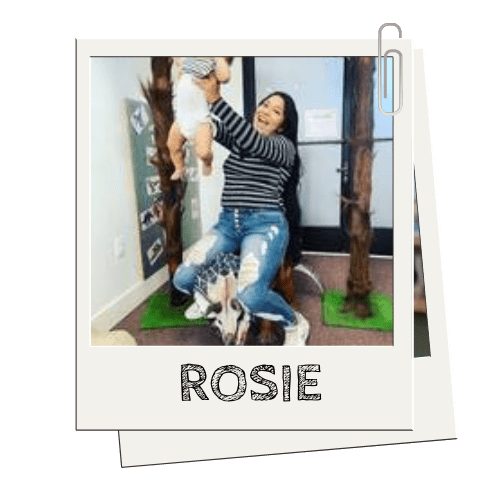 Person sitting in play area, holding a child up, name 'ROSIE' on image.