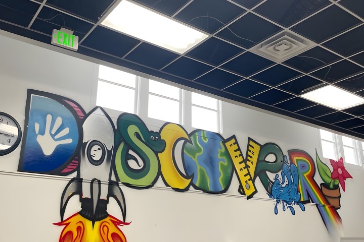 Colorful mural spelling 'DISCOVER' with various themed letters and illustrations on a classroom wall.