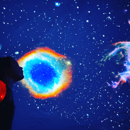 Person silhouetted against vibrant, colorful galaxy and starry sky.