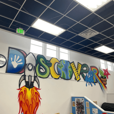 Colorful mural spelling 'DISCOVER' with rocket, earth, and flowers.