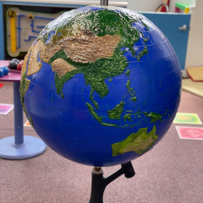A colorful globe showing Asia and Australia on a stand in a room.