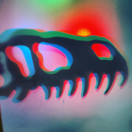 Colorful dinosaur skull silhouette with vibrant red, green, and blue hues.