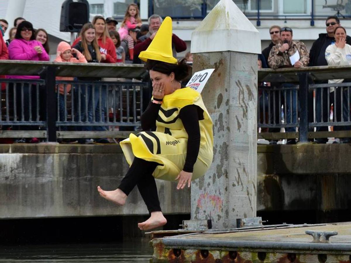 Person in crayon costume jumping into water from dock, crowd watching in background.